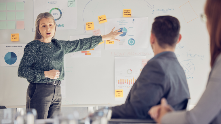 Woman presenting data analysis at a whiteboard in an office